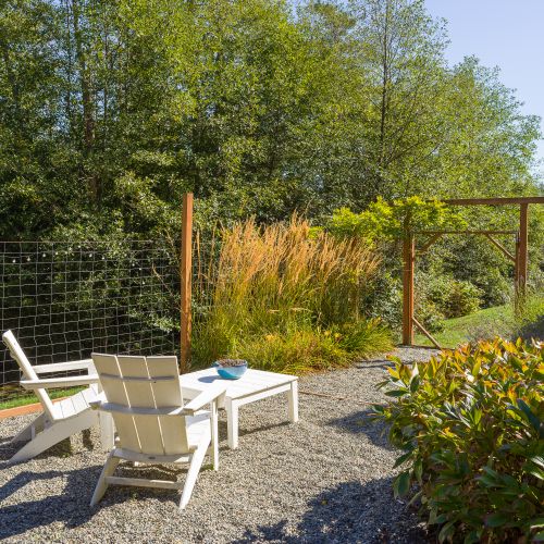 Secluded gravel seating area in a lush garden setting.