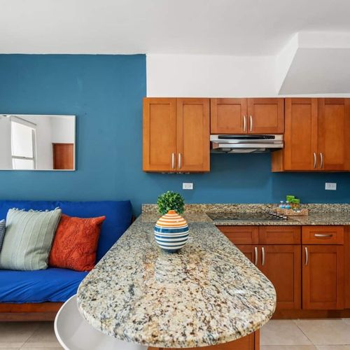 Inside a well-lit apartment, the living area flows seamlessly into an open kitchen.