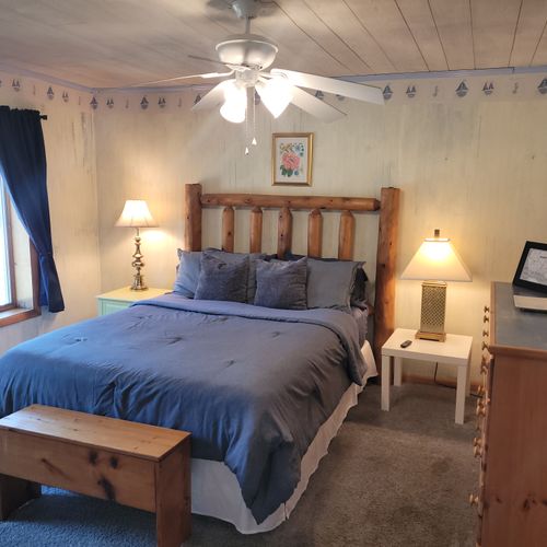 BEDROOM #1 (MAIN FLOOR):  Features a queen-size bed, dresser, mirror, closet, rocking chair, private ensuite bathroom, and private live-streaming television.  (Note that there is a collapsing curtain between the bedroom and the living room.)