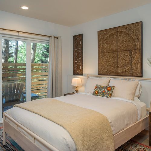 Intricate carved wood art, crisp linens, and a private deck door — the second bedroom is a serene escape with soul.