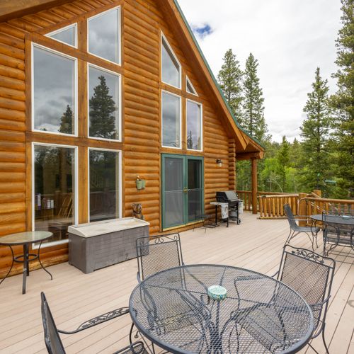 Expansive outdoor log deck with bbq grill, patio seating with an infinite backdrop of the rocky mountains.