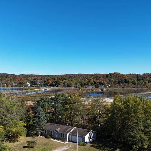 EXTERIOR:  Aerial photo of the home in late summer with the Betsie River in the background