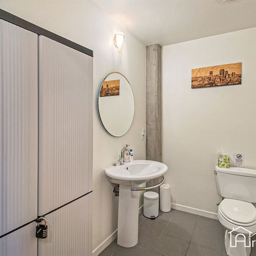 - clean and modern half bath with a round mirror, pedestal sink, and cityscape art
- concrete accent column adds a touch of urban style to the minimalist design
- convenient extra space for guests or quick freshen ups during your stay