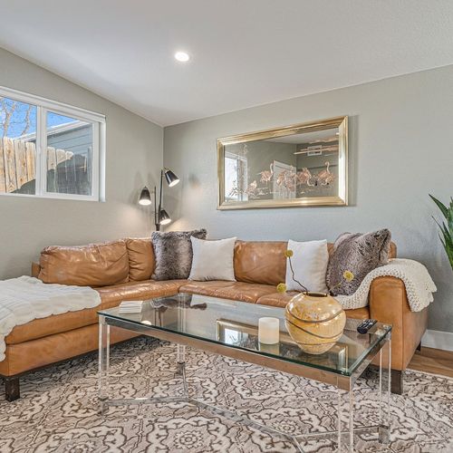 - cozy corner lounge with plush leather sectional, soft throw, and statement gold mirror
- glass coffee table holds curated accents for a clean, elevated feel
- neutral palette and indoor plant add balance to the relaxed design