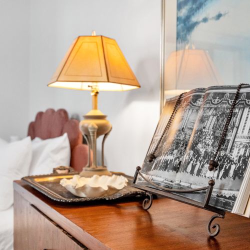Cozy bedside setup w/ a warm lamp & a stack of curated books.