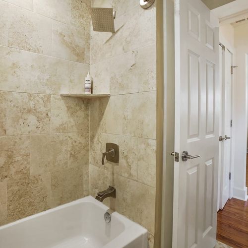 Refresh and rejuvenate in this modern bathroom, featuring a luxurious rainfall showerhead and elegant tilework. The spacious tub is perfect for a relaxing soak after a day of exploring all that New Orleans has to offer