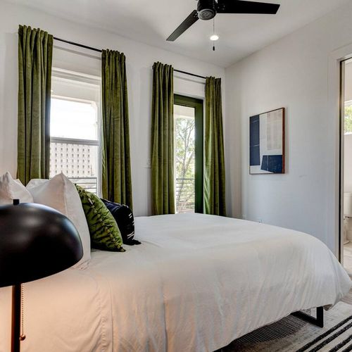 Upstairs bedroom w/ lush green curtains, warm tones & a relaxed vibe.