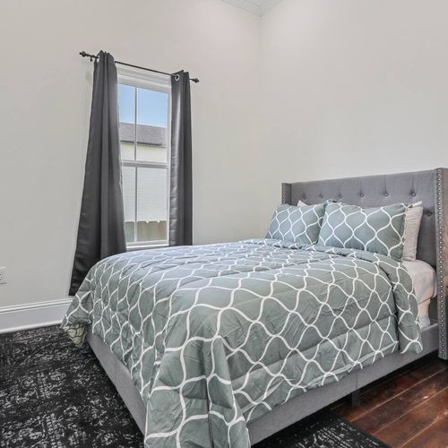 Restful bedroom w/ a patterned comforter & soft natural light.