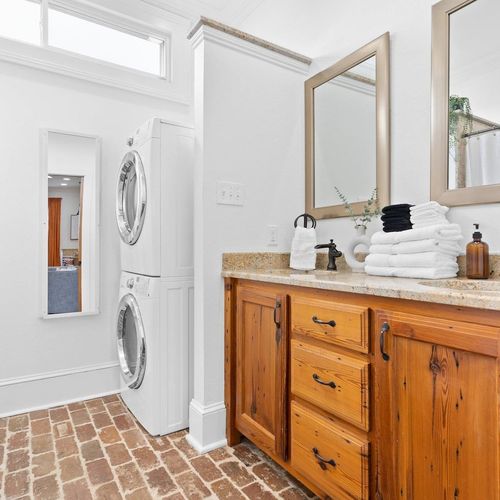 Clean bathroom w/ warm wood vanity & ample counter space for getting ready.