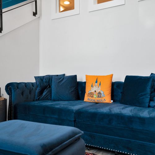 Sink into a plush blue velvet sofa w/ a cheerful orange pillow accent.