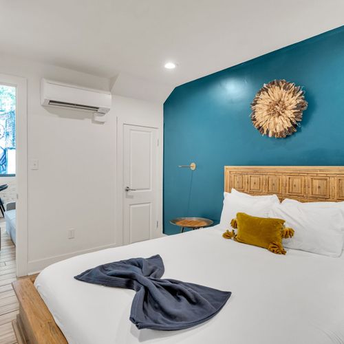 Unwind in a stylish bedroom with a comfy king bed, bold accent wall, and warm natural light. Perfect for couples or solo travelers looking for a relaxing stay near all the New Orleans action.