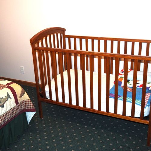 Bedroom #2 (lower level):  features a king-size bed, dresser, chair, table, and crib.