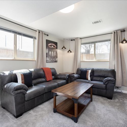 Stylish lounge, which is complete with a plush sectional, two leather lounge chairs, a coffee table, and a big window letting in a ton of light.