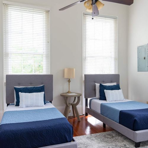 Bright and inviting twin bedroom with stylish bedding and ample natural light. This room offers a comfortable setup, perfect for friends or family members to unwind and enjoy a restful stay in New Orleans.