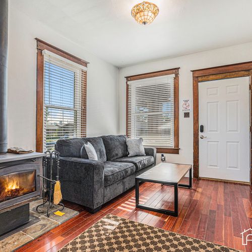 The living room beckons with a queen pull-out couch, smart tv, and the warmth of a wood-burning stove with wood provided.
