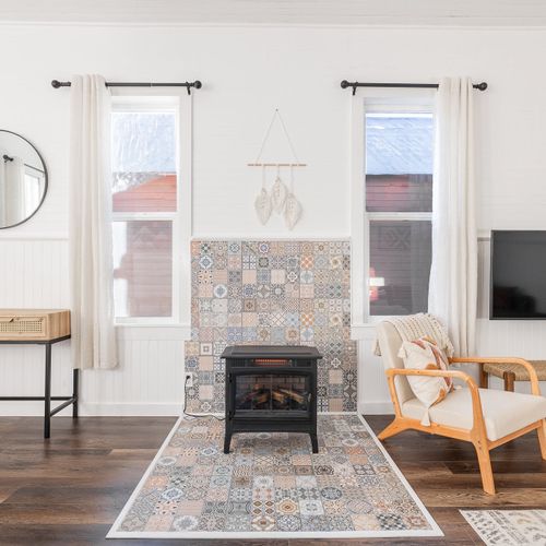 A freestanding electric fireplace sits atop the eclectic mosaic tiles in the main living space.