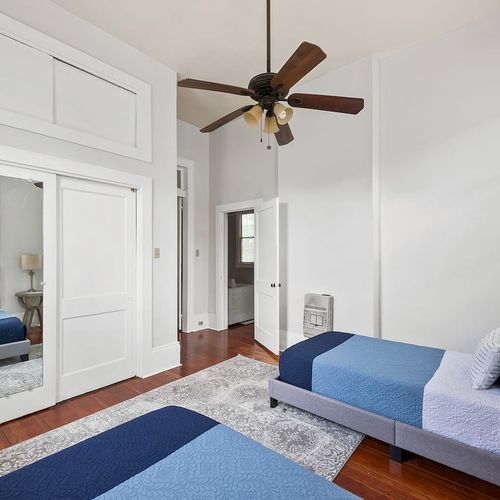 Spacious and airy twin bedroom with ample closet space and mirrored doors, adding to the room's open feel. Perfect for guests looking for a comfortable and stylish place to rest after exploring New Orleans.