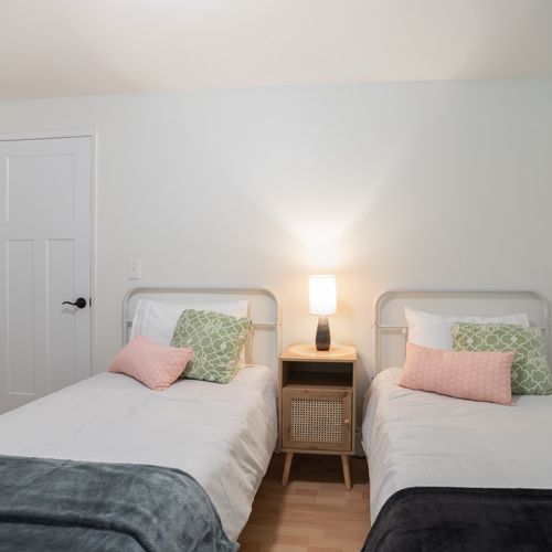 Upstairs guest bedroom with twin beds, extra blankets, and pillows.