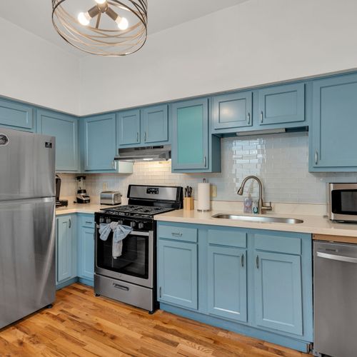 Fully equipped kitchen w/ stainless steel appliances & blue cabinetry.