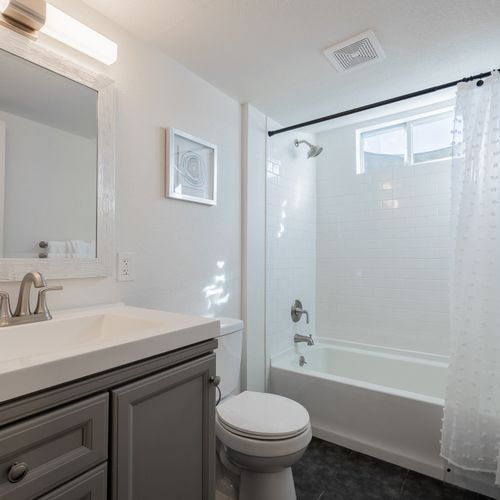 Experience spa-like amenities in the fully remodeled bathroom featuring a large tub/shower combo, extended modern vanity and ambient lighting.