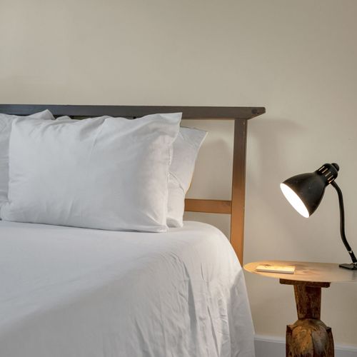 Softly lit bedroom w/ a plush bed & warm, inviting linens.