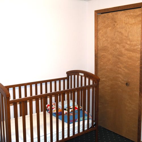 Bedroom #2 (lower level):  features a king-size bed, dresser, chair, table, and crib.