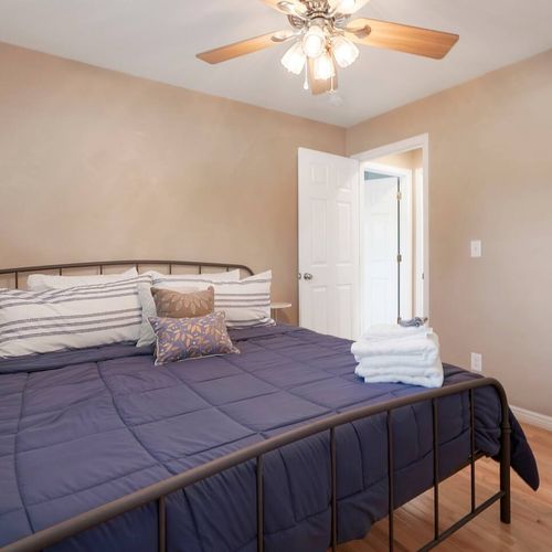 - neutral toned bedroom with king bed, striped pillows, and plush navy comforter
- ceiling fan above and wood floors below provide all season comfort
- conveniently located near the bathroom for easy access during your stay