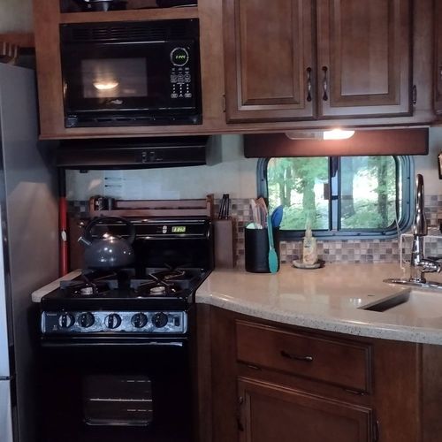 Kitchen:  the home has a cute little kitchen with a refrigerator, sink, counter, stove, oven, and microwave. There is also a collection of cooking and dining utensils provided.