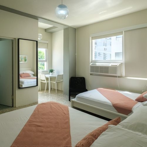 Discover comfort and space in this bright bedroom, featuring a plush bed and a full-length mirror, perfect for getting ready to explore the city or a last-minute check before heading out.