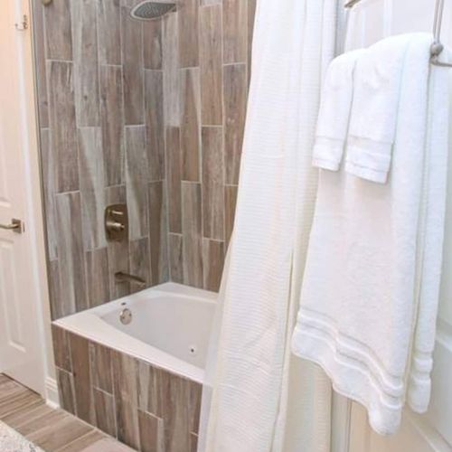 Spa-like bathroom w/ earthy tile & neatly folded fresh towels.