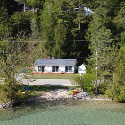 Exterior:  a great aerial photo with crystal lake, the private beach, lakefront, bonfire ring, and kayaks in the foreground. The cottage itself is in the background.