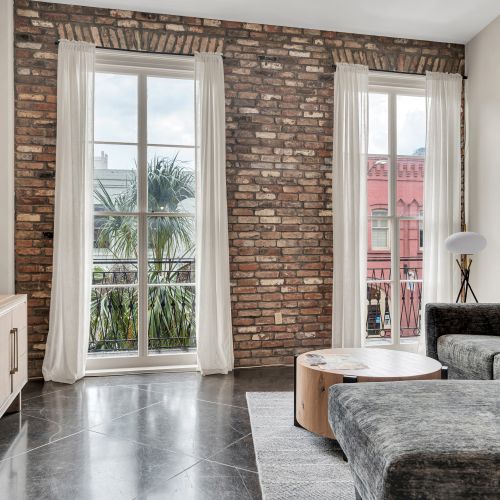 Sun-drenched living room w/ exposed brick & floor-to-ceiling windows.