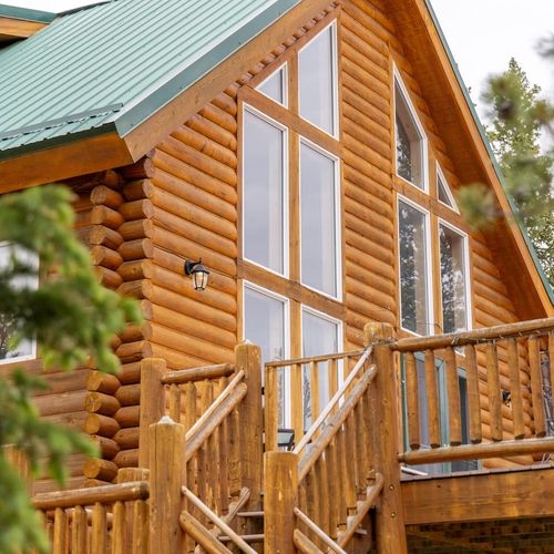 Close up of the large a frame windows and wood railings that define the cabin’s classic mountain charm.