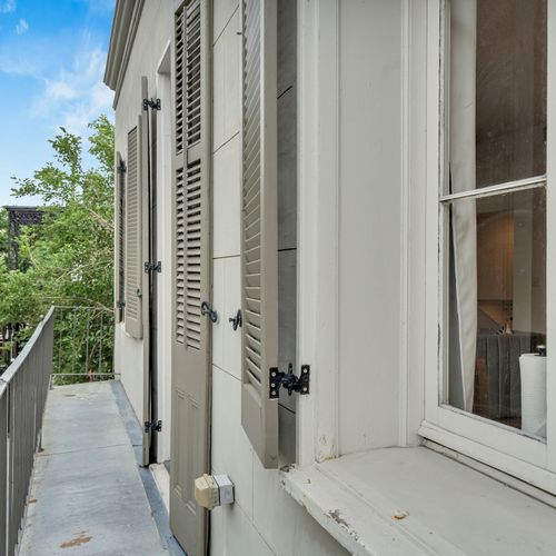 Charming balcony with classic shutters—perfect for a quiet moment overlooking a peaceful New Orleans street.