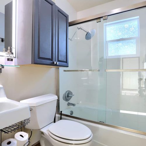 - clean and bright full bathroom with glass enclosed shower and tub combo for refreshing rinses
- wall mounted cabinet and under sink storage help keep toiletries organized
- natural light filters in through frosted glass for a spa like touch