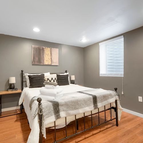 - stylish lower level bedroom with deep gray walls and cozy lighting throughout
- modern black bed frame and layered bedding create a sleek, restful space
- wood floors and soft light make it inviting and perfect for deep sleep