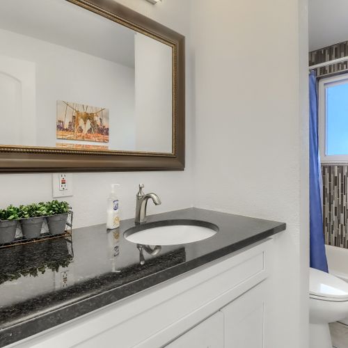 The shared hall bathroom features an extended vanity and fully tiled shower/tub option. For added convenience, there is a second bathroom with a stand in shower on the lower floor.