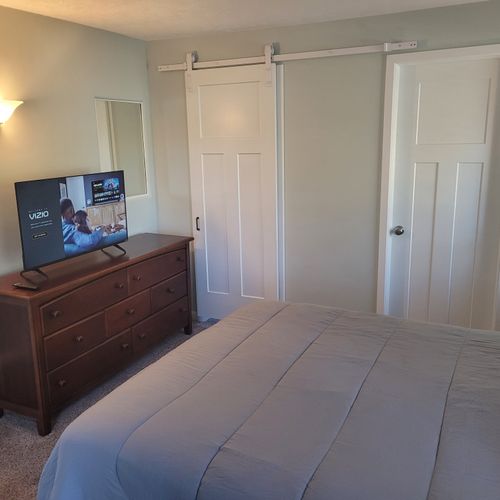 Bedroom #1:  features a queen-size bed, private en suite full bathroom, private television, walk-in closet, dresser, mirror, nightstands, and lamps
