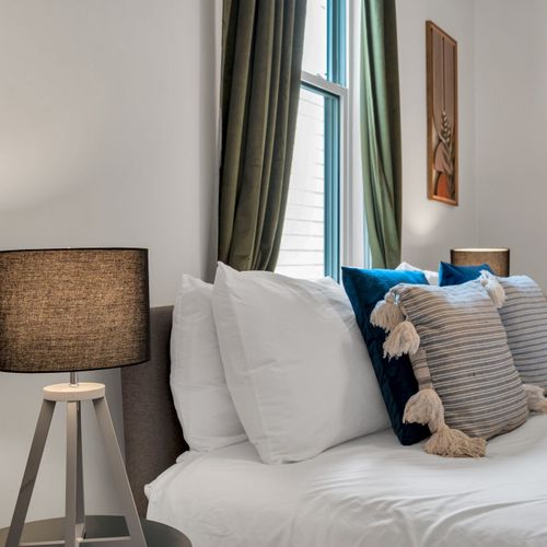Bed dressed in soft, layered pillows & crisp linens for a boutique-hotel feel.
