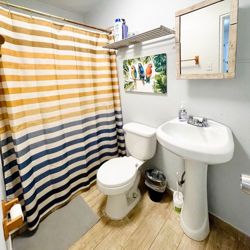 Refresh and rejuvenate! Our clean and modern bathroom features a spacious shower with a fun, striped curtain, ensuring a bright start to your day.