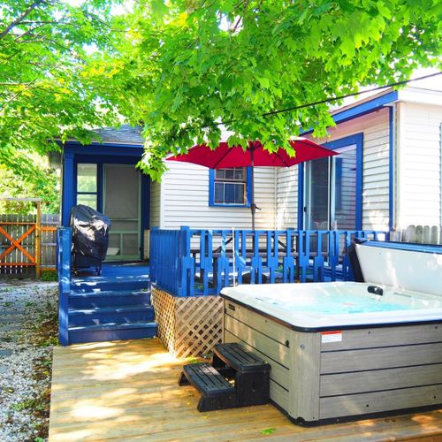 Exterior:  the fully fenced-in backyard with newly expanded deck, new hot tub, bonfire ring, propane grill, and picnic table with umbrella.
