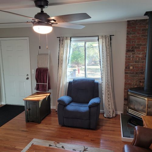 Living room:  comfy living room with a sofa, gas fireplace, live streaming television, coffee table, comfy chair, and ceiling fan.
