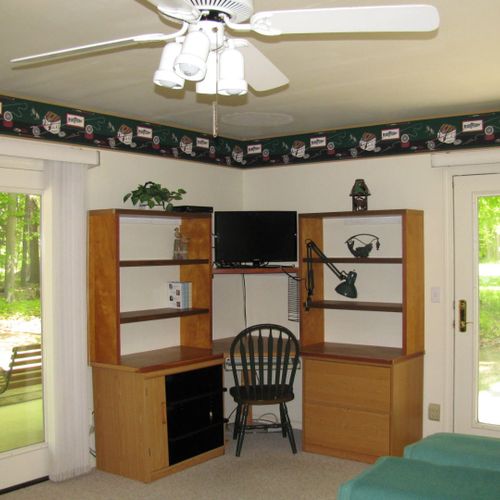 Bedroom #1:  the cabin has a large primary bedroom with a queen-size bed, desk, comfy chair, ceiling fan, dresser, and closet.