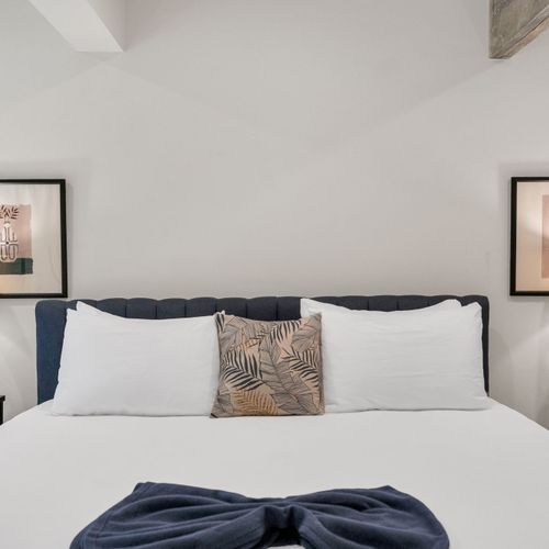 Comfortable bed w/ crisp linens in a simply styled, restful room.