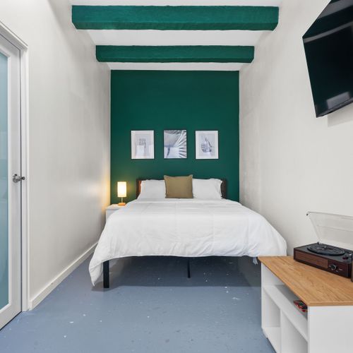Generous bedroom offering a plush bed, flat-screen TV, and a window letting in refreshing air.