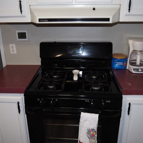 A close-up of the gas range and the coffee maker.
