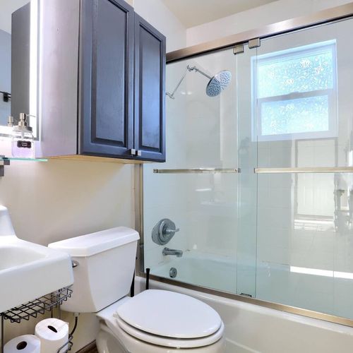 - treat yourself to a spa like experience with the stylish rain showerhead
- elegant black cabinetry contrasts beautifully with clean white fixtures
- glass doors, led lit mirror, and natural light create a fresh, polished vibe
