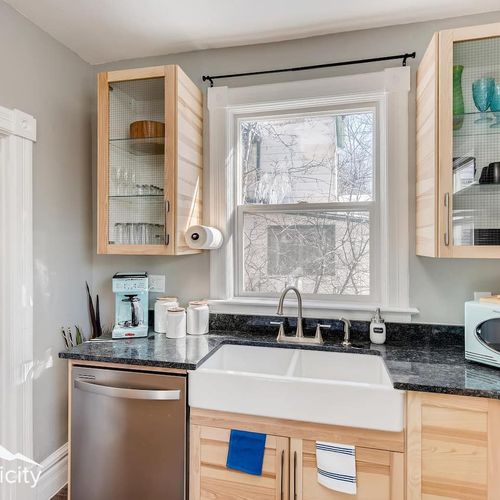 - bright kitchen corner with a farmhouse sink, glass cabinets, and stylish granite countertop
- equipped with a coffee maker, microwave, toaster, and essential cookware
- natural light pours through the window for a fresh and airy feel