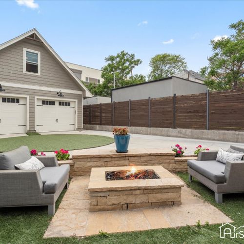 A captivating photo of the driveway area and backyard, featuring a central patch of vibrant green turf that adds a touch of freshness to the outdoor space.
