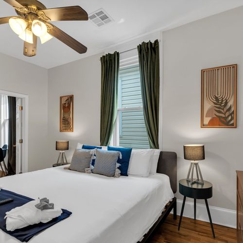 Airy bedroom w/ a neatly made bed & warm natural light.